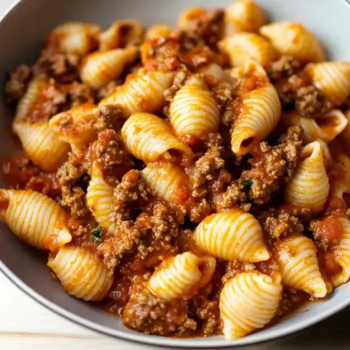 A bowl of pasta shells mixed with ground meat and marinara sauce.